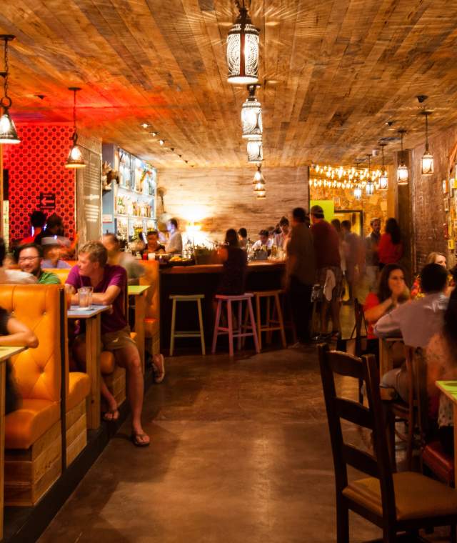 People sitting in booths inside The Pastry War in Houston